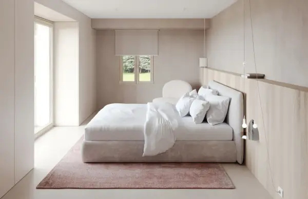 Chambre épurée avec lit blanc, tapis rose poudré et bois clair. Une belle inspi déco chambre pour un cocon de douceur.