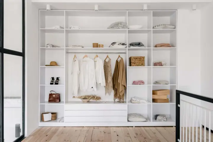 Idéal pour aménager un placard : étagères blanches remplies de vêtements, accessoires et boîtes.